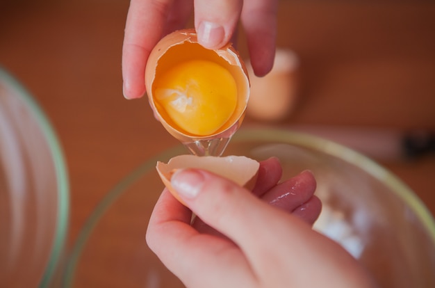 Una donna che tiene un uovo di gallina aperto nelle sue mani