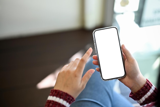 Una donna che usa il suo smartphone Immagine del primo piano del mockup dello schermo bianco del telefono