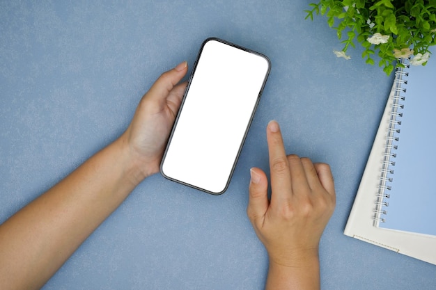 Una donna che utilizza il suo smartphone su un'elegante area di lavoro blu nella vista dall'alto sullo sfondo