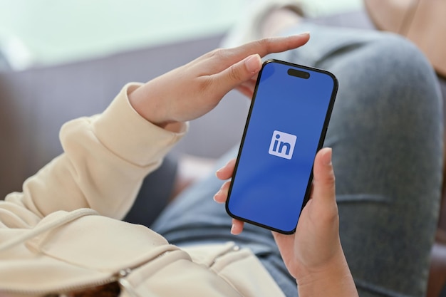 Una donna che utilizza l'applicazione LinkedIn sul suo telefono iPhone con il logo LinkedIn sullo schermo