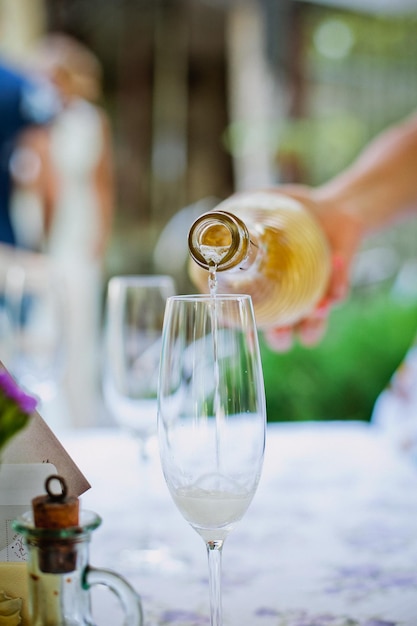 Una donna che versa una bottiglia di vino bianco in un bicchiere