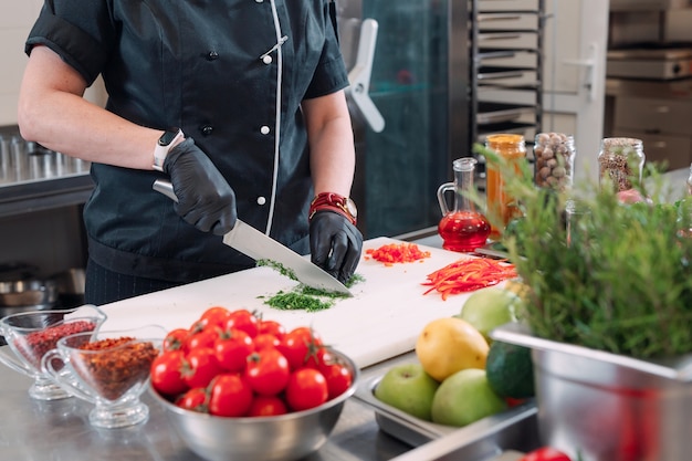 Una donna Chef taglia le verdure in cucina in un ristorante