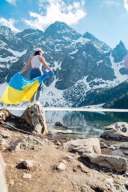 Una donna con bandiera ucraina è in piedi sulla riva del lago Morskie Oko