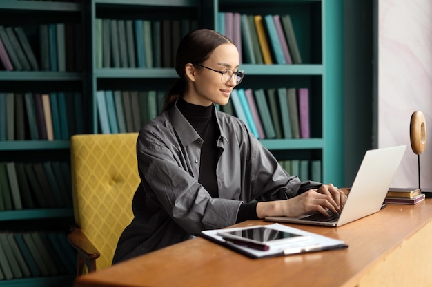 Una donna con gli occhiali è una freelance che lavora in uno spazio di coworking usa un laptop e fa