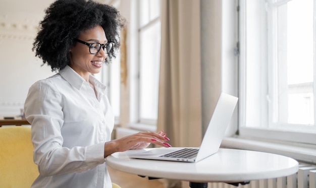 Una donna con gli occhiali in ufficio sta lavorando a un progetto di avvio utilizzando un laptop