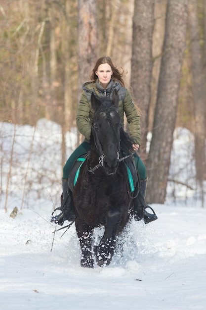 Una donna con i capelli lunghi che cavalca un cavallo marrone scuro nella foresta