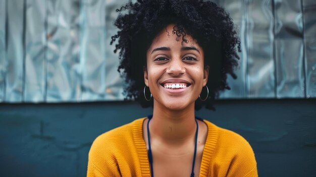 Una donna con i capelli ricci sta sorridendo e indossa un maglione giallo