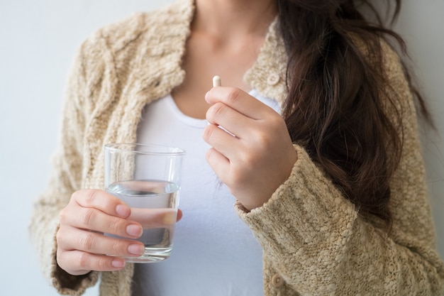 Una donna con in mano una medicina e un bicchiere d&#39;acqua. Concetti medici e sanitari