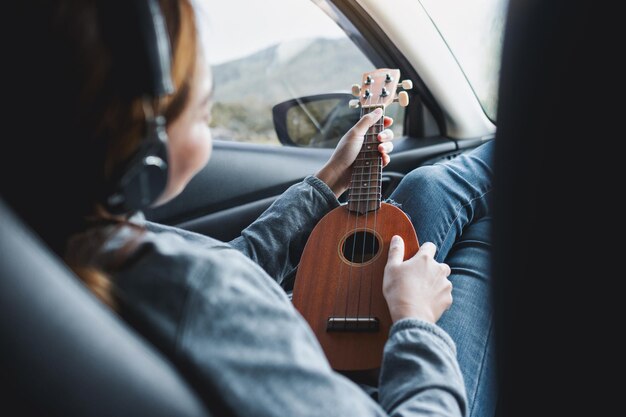 Una donna con le cuffie che suona l'ukulele mentre è in macchina