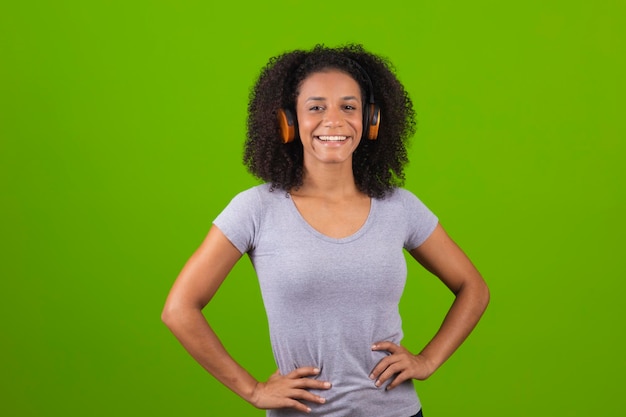 Una donna con le sue cuffie si trova davanti a uno sfondo verde.