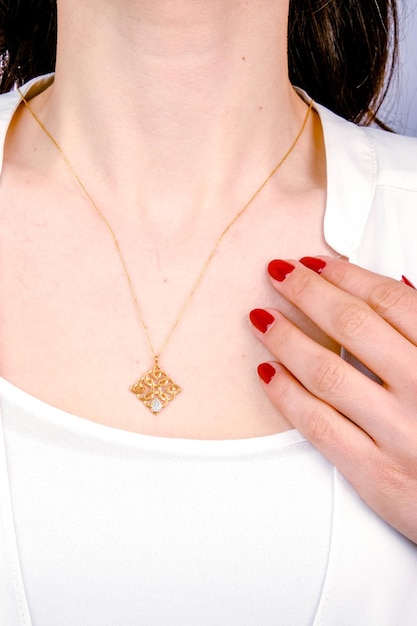 una donna con lo smalto rosso per unghie tiene una croce al collo