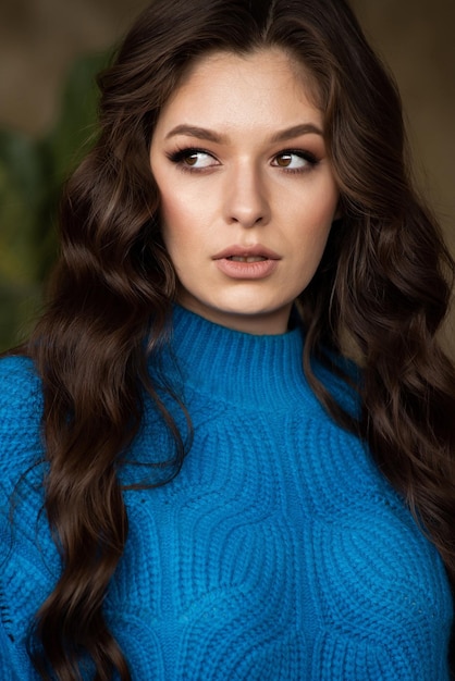 Una donna con lunghi capelli castani e un maglione blu
