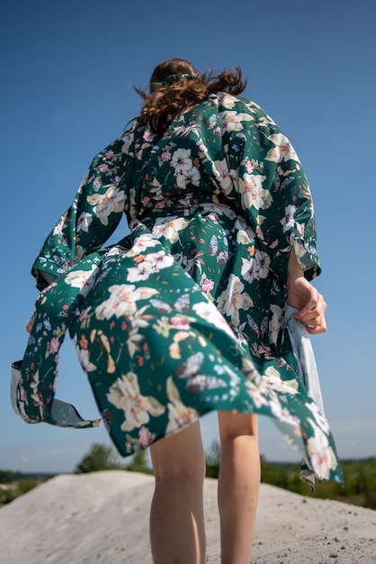 Una donna con un abito floreale verde sta camminando lungo un lago.