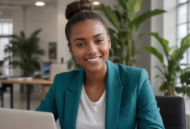 Una donna con un blazer azzurro sorride mentre lavora su un portatile in un ambiente di ufficio luminoso