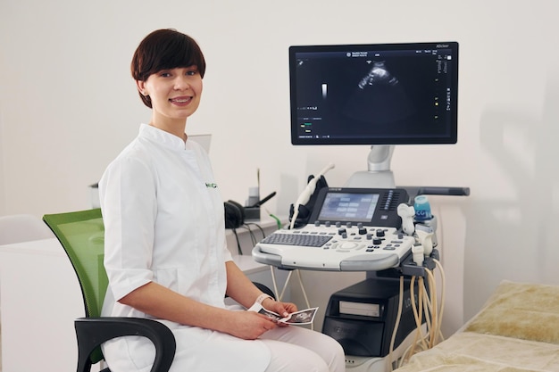 una donna con un camico bianco si siede davanti a un monitor che dice medico