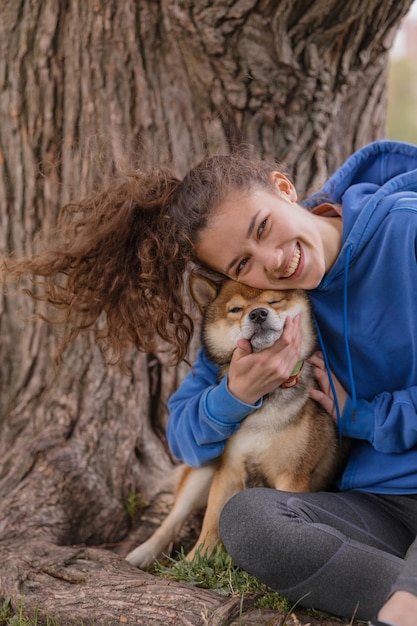 Una donna con un cane nel parco fa sport o fitness su un tappetino da yoga una donna europea con ricci