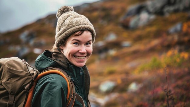 Una donna con un cappello e uno zaino su un sentiero di montagna sorride felicemente