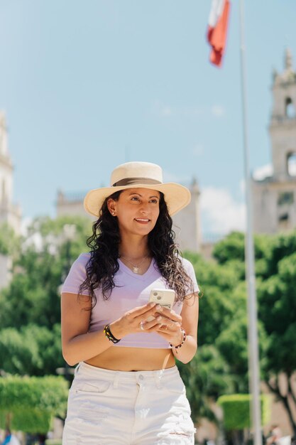 Una donna con un cappello si trova di fronte a un edificio e sorride