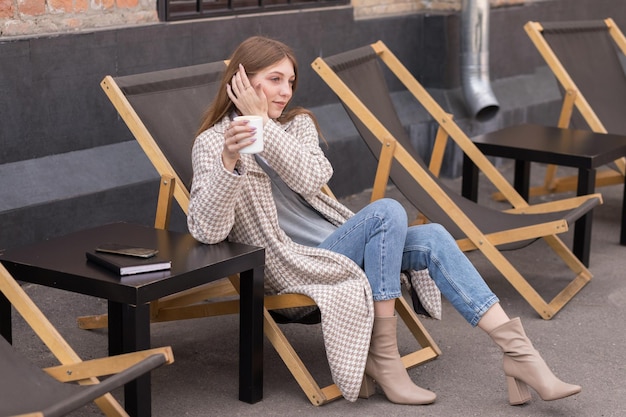 Una donna con un cappuccino in un blog di un caffè di strada