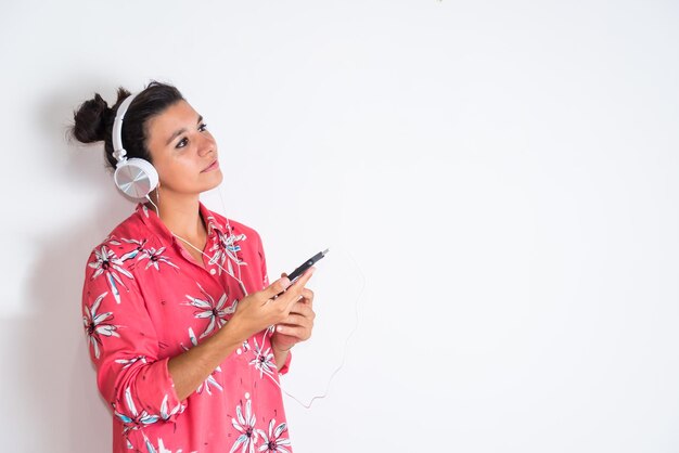 Una donna con un cellulare in mano e le cuffie che ascoltano musica nostalgica
