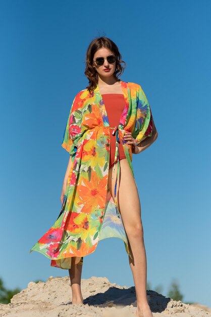 Una donna con un kimono colorato si erge su una collina di fronte a un cielo blu.