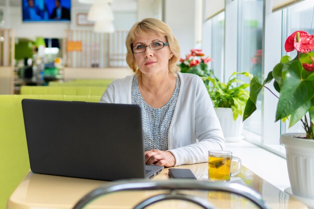 Una donna con un laptop sta lavorando in un ufficio. Una donna di mezza età è una donna d'affari in un caffè. Fa il lavoro.