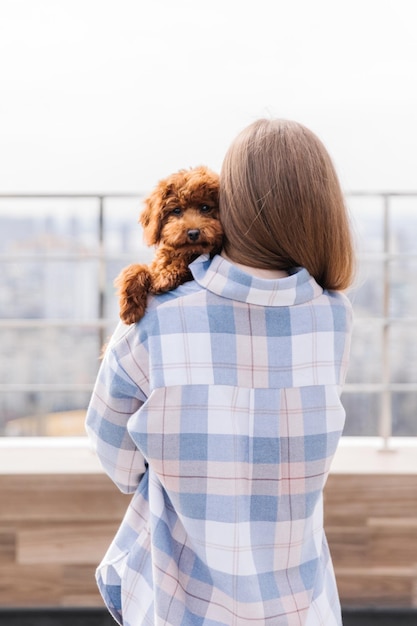 Una donna con un pigiama scozzese blu tiene in braccio un cane.