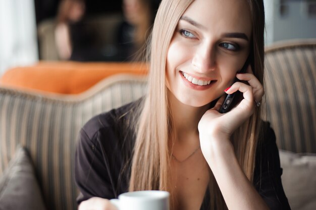 Una donna con un sorriso carino con la conversazione di telefonia mobile