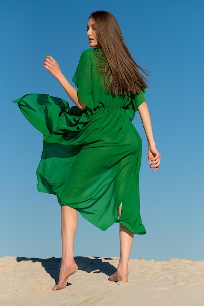 Una donna con un vestito verde sta camminando su una spiaggia