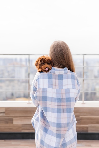 Una donna con una camicia a quadri tiene un cane sulla spalla.
