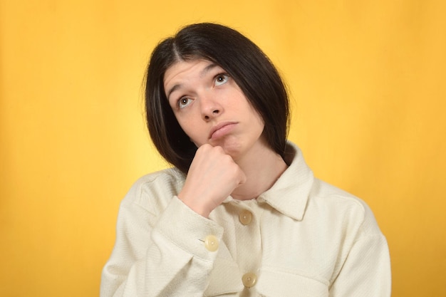 Una donna con una camicia bianca e una camicia in piedi davanti a uno sfondo giallo