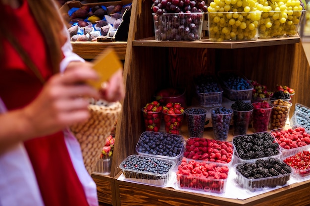 Una donna con una carta di credito in mano mentre paga della frutta in un negozio