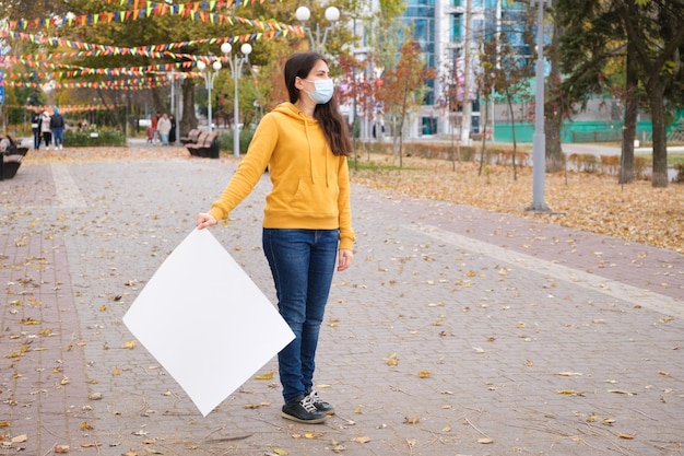 Una donna con una maschera medica tiene un lenzuolo bianco vuoto