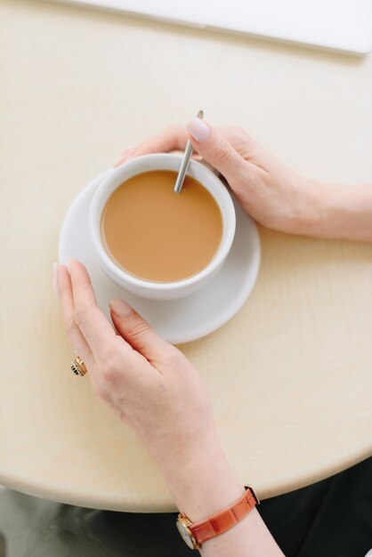 Una donna con una tazza di caffè in un caffè all'aperto d'estate