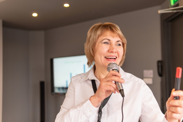 Una donna conduce un corso di formazione in un centro commerciale. Donna di mezza età in un ufficio con un microfono