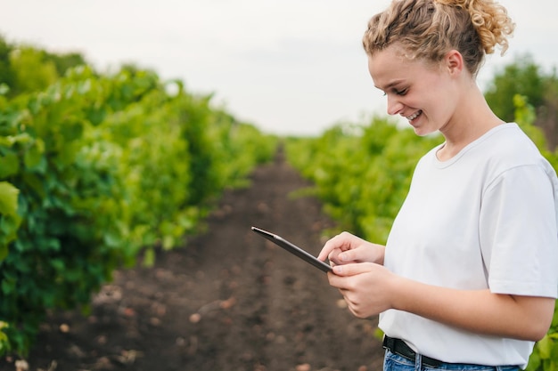 Una donna contadina esamina con tablet lavorando in vigna in estate Copia spazio Concetto di industria intelligente Tecnologia Internet