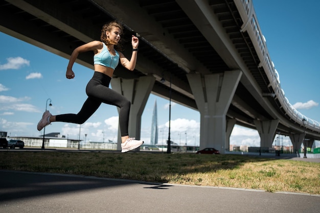 Una donna corre su un ponte con un edificio sullo sfondo.