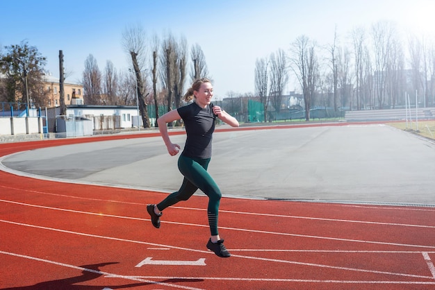 Una donna corre sulla pista dello stadio. Allenamento fitness estivo. Corsa, sport, stile di vita sano e attivo.