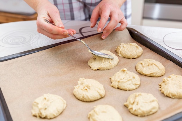 Una donna cucchiai di pasta biscotto su una teglia Home cottura e cucina Closeup