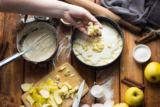 Una donna cucina una torta di mele su un tavolo di legno. Il processo di fare una torta.