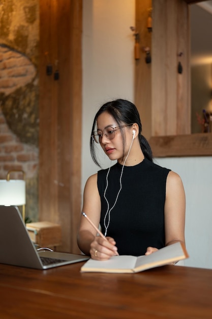 Una donna d'affari asiatica concentrata sta tenendo una riunione online o studia online mentre è seduta in un bar