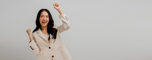 Una donna d'affari asiatica di successo e attraente alza la mano per festeggiare il successo e la donna felice in abito bianco isolata in studio