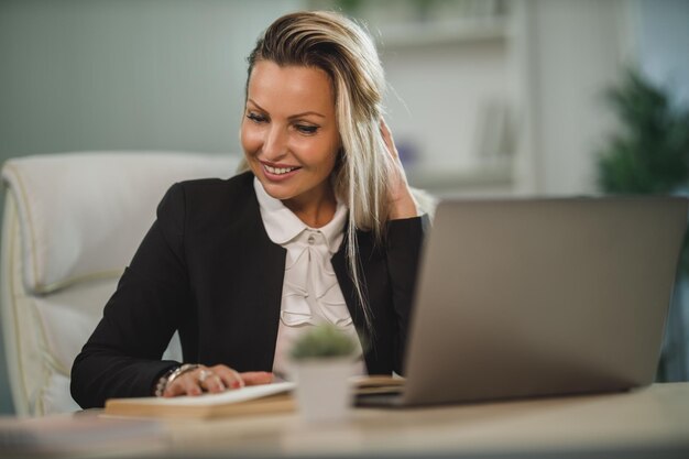 Una donna d'affari attraente sicura di sé seduta alla sua scrivania in ufficio e al lavoro.