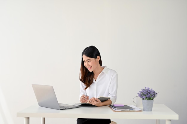 Una donna d'affari che guarda lo schermo del suo laptop e lavora sui suoi compiti alla sua scrivania