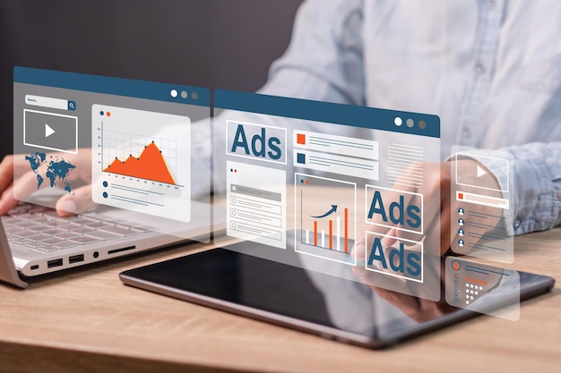 Una donna d'affari che lavora su un portatile e un tablet per promuovere un prodotto o un servizio su un sito web, e-mail e social media Concetto di marketing digitale