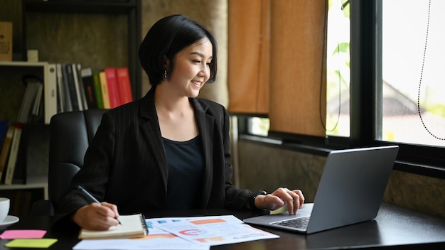 Una donna d'affari che lavora sui suoi compiti aziendali utilizzando il computer portatile alla sua scrivania