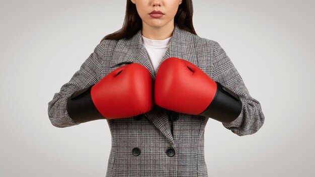 Una donna d'affari determinata con guanti da boxe in abito da lavoro.