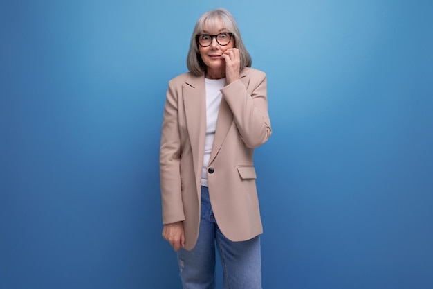 Una donna d'affari di mezza età in un look elegante si erge pensierosa su uno sfondo di studio con copia