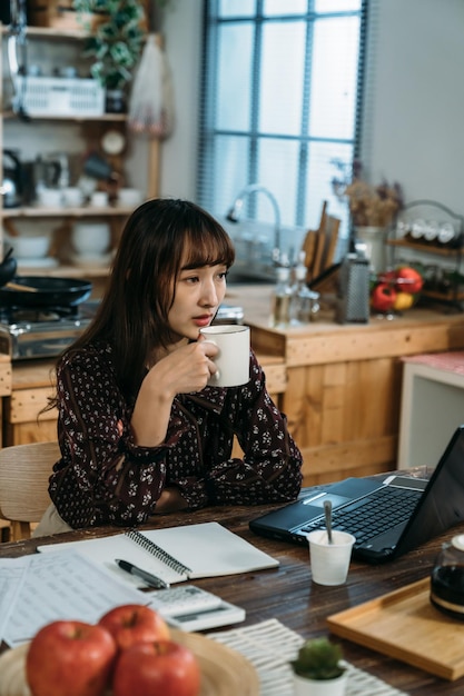 Una donna d'affari distratta ha il tè caldo e non ha voglia di prepararsi per l'esame interno per i dipendenti in arrivo. concetto di lavoro da casa.