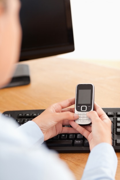 Una donna d&#39;affari in possesso di un telefono cellulare sul posto di lavoro